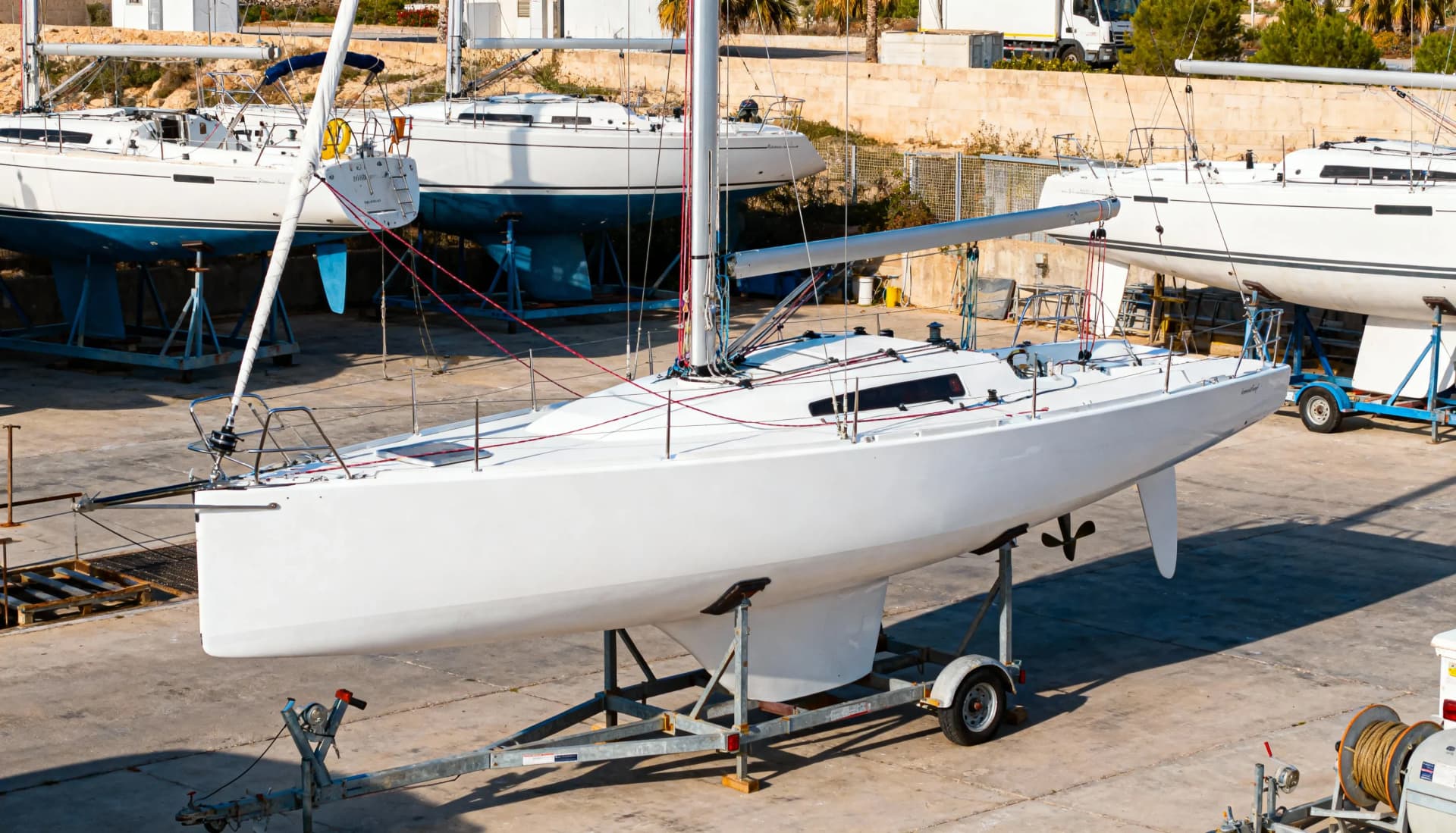 Velero monótipo de competición fuera del agua en astillero de Alicante mostrando el casco completo, quilla, timón y todo el aparejo, utilizado en la Liga de Monotipos